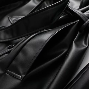 Detailed close-up of premium black leather coat with stitching and belt pocket details