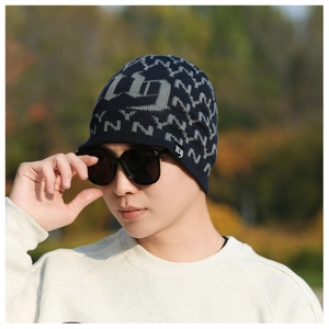 Detailed close-up of navy blue winter beanie featuring knitted letter patterns and textures