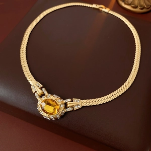 Detailed close-up of vintage gold snake chain necklace with oval yellow gemstone and zircon