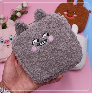 Close-up of fuzzy gray plush storage pouch with embroidered cartoon face and zipper detail