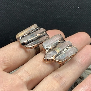 Detail of two vintage bronze rings featuring raw white crystal pillars on fingers