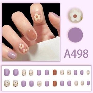 Detail view of 24pcs short round press-on nails with purple floral patterns and nude finish