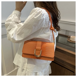 Detail of orange crocodile pattern crossbody bag with gold U-lock and knotted strap