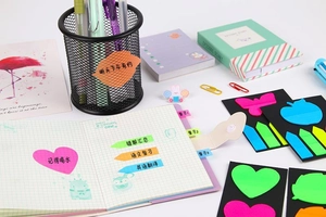 Detail of colorful PET index tabs with heart and arrow shapes on a notebook