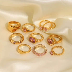 Set mit 10 Goldringen mit rosa Zirkonia und Herzdesigns auf beigem Seidenstoffhintergrund