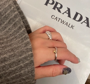 Close-up of minimalist S925 sterling silver twisted band ring with gold bead detail