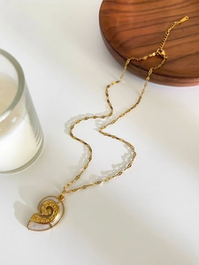 Detailed macro view of golden shell pendant with white mother-of-pearl inlay