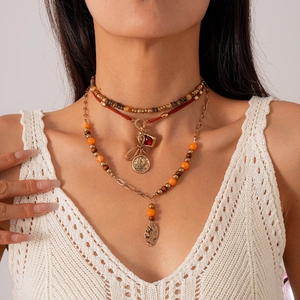 Detail of bohemian layered necklace with red beads, gold coin, and gemstone pendants