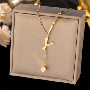 Detailed shot of golden Y letter necklace with minimalist cube pendant on a jewelry box