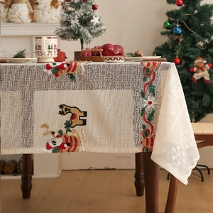 Close-up of reindeer embroidery and white snowflake lace on beige Christmas tablecloth