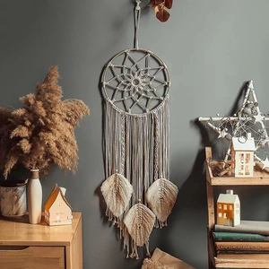 Detailed view of beige handmade woven dreamcatcher tapestry with tassels on a grey wall