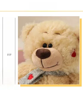 Primer plano del oso de peluche crema con pelaje suave y bufanda de punto gris con corazón