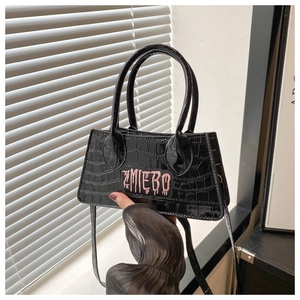 Detail of black crocodile texture mini bag with pink ZMIEBO embroidery and shoulder strap