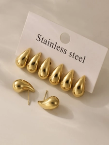 Macro detail of four pairs of gold teardrop earrings on a stainless steel card