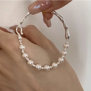Macro detail of elegant pearl and silver irregular liquid metal bracelet on wrist