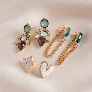 Détail de boucles d'oreilles cœur en zircon et résine sur soie beige