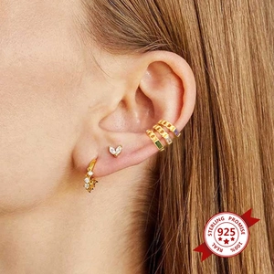 Détail de boucles d'oreilles en argent doré avec zircons colorés portées par un mannequin