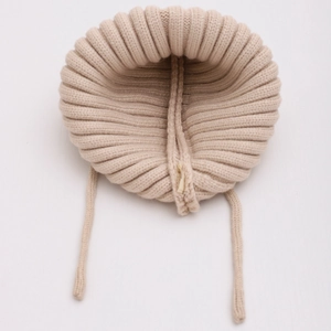 Detailed close-up of beige knitted baby bonnet showing ribbed texture and earflaps