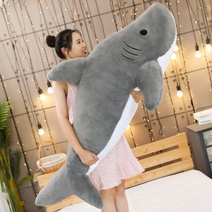 Detailed view of giant grey and white shark plush pillow held by model in bedroom