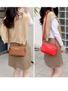 Close-up of brown and red quilted crossbody camera bags with elegant gold letter logos