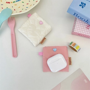 Detail of heart-quilted soft shell mini pouches for AirPods in cream and pink colors