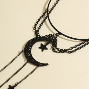 Detail of gothic black multi-layer chain with moon and star pendants on beige background