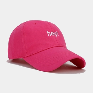 Detail of pink cotton baseball cap featuring white 'hey!' embroidery and 6-panel design