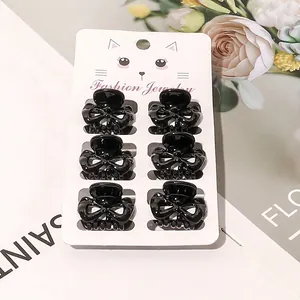 Set of six black mini heart-shaped hair claws on a fashion display card