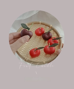 Detalle de mini velas aromáticas con forma de cereza en una bandeja, detalles de fruta real