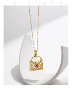 Détail du collier pendentif sac à main doré avec pierre rouge goutte d'eau et zircons