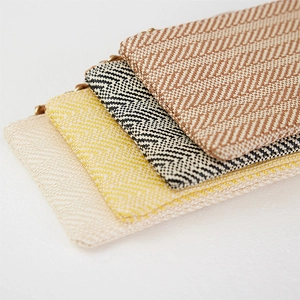 Detail of four woven straw coin purses in beige, yellow, black and brown herringbone patterns