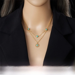 Detail of layered gold sun pendant necklace with turquoise stones on model