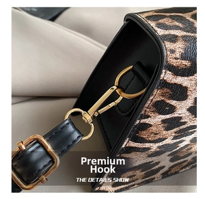 Macro view of gold metal rotating hooks and black leather strap on leopard print bag