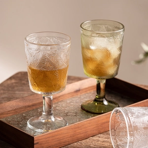 Vintage embossed glass goblet with elegant leaf pattern on a wooden serving tray