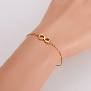 Élégant collier doré avec symbole de l'infini et cristaux sur une chaîne délicate
