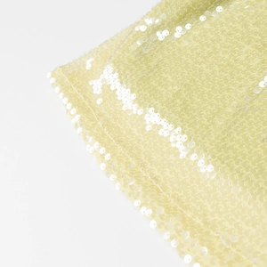 Détail rapproché du tissu à paillettes jaune pâle avec doublure en maille pour jupe