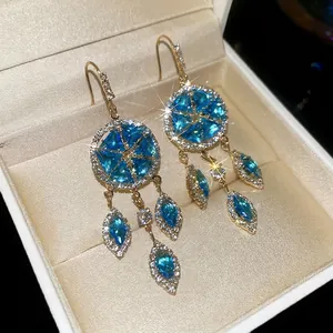 French palace style gold drop earrings with blue starburst gems and diamond accents