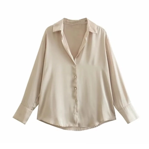 Détails de la texture satinée et du col boutonné sur cette chemise champagne