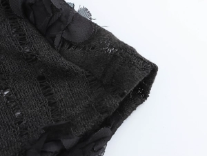 Gros plan sur la manche d'une robe noire en maille ajourée avec bordure en dentelle fleurie