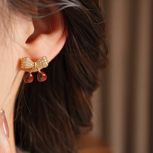Vue latérale macro de boucles d'oreilles cerises avec zircons portées par un mannequin