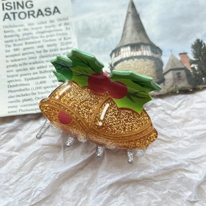 Detail of Christmas bell hair claw clip with golden glitter and green holly leaves
