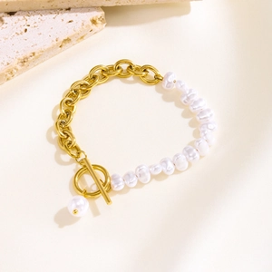 Baroque pearl and gold chain bracelet with OT toggle clasp on a textured background