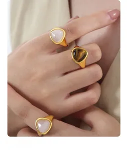Detail of matte gold rings set with natural tiger eye and pink crystal on hand