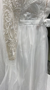 Gros plan détaillé de la broderie en dentelle blanche et de la ceinture à nœud de la robe