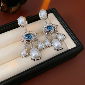 Detailed macro view of vintage silver earrings with blue eye motif and white pearl tassels