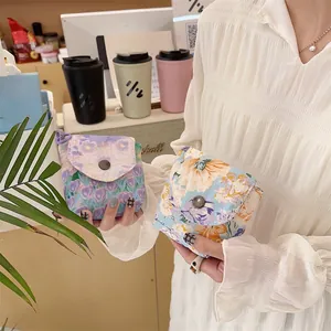 Detail of floral fabric mini pouches with metal button closure held in hand