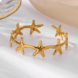 Detailed macro view of the golden starfish charm on the stainless steel open bangle