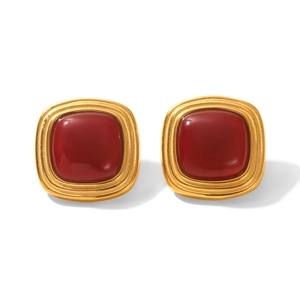 Macro detail of gold stainless steel stud earrings featuring round red gemstones