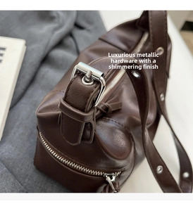 Close-up of polished silver buckle on dark brown leather shoulder strap detail