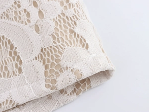 Detailed macro view of white floral lace fabric with beige lining for women clothing